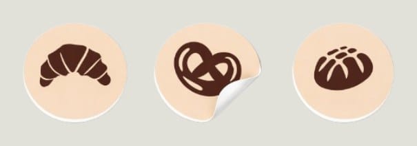 Three round stickers with a croissant, a pretzel and a bread roll in dark brown